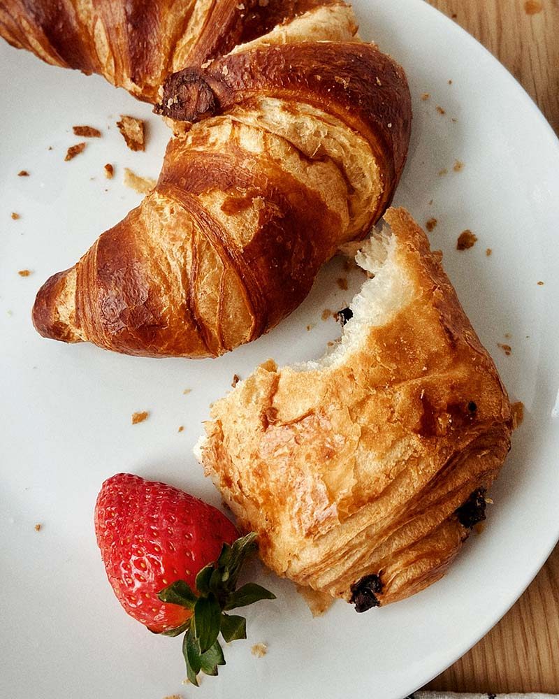 A kosher croissant and a strawberry on a plate. Richmond Kosher Bakery