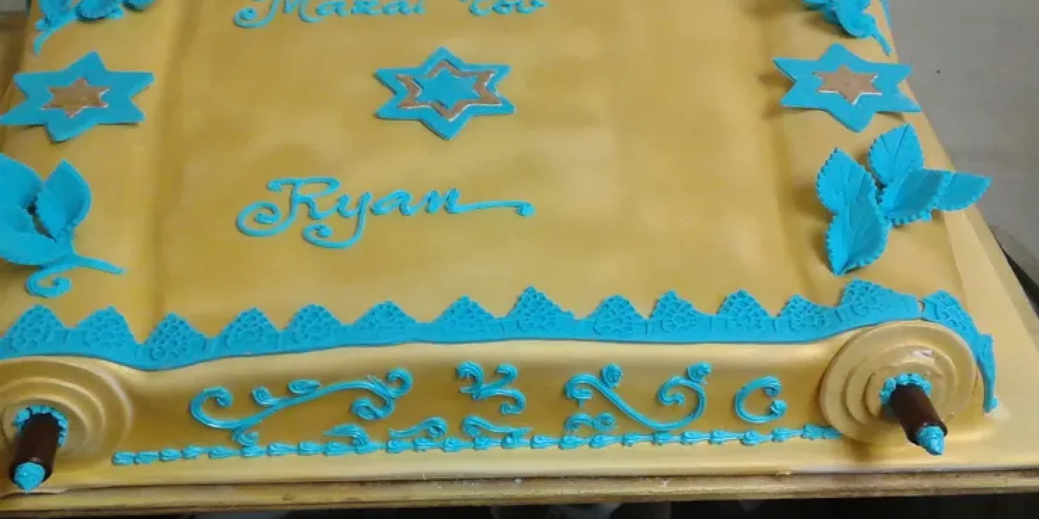 A Kosher cake adorned with blue and gold decorations. Richmond Kosher Bakery