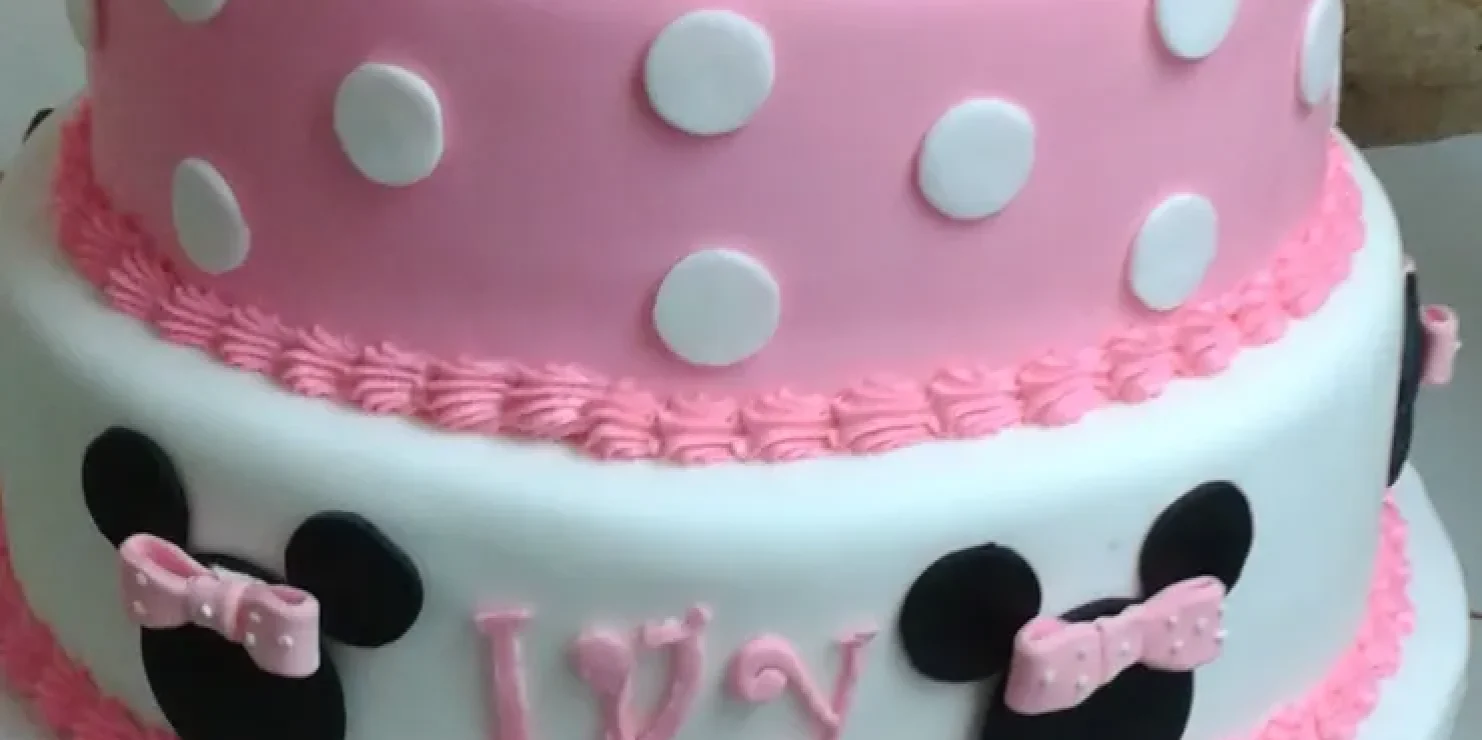 A kosher minnie mouse cake in hues of pink and white, adorned with polka dots. Richmond Kosher Bakery